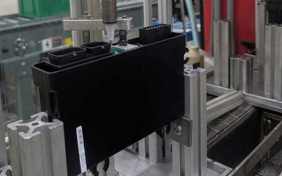 Automated dispense head filling a module housing on the potting cell at Soaris